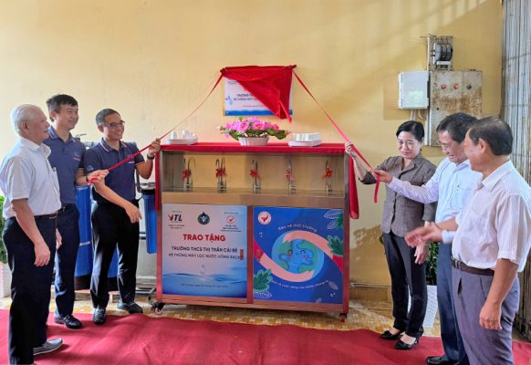 Đâị điện chính quyền và đơn vị tài trợ kéo vải đỏ khánh thành dự án máy lọc nước cho các trường học tại Cái Bè